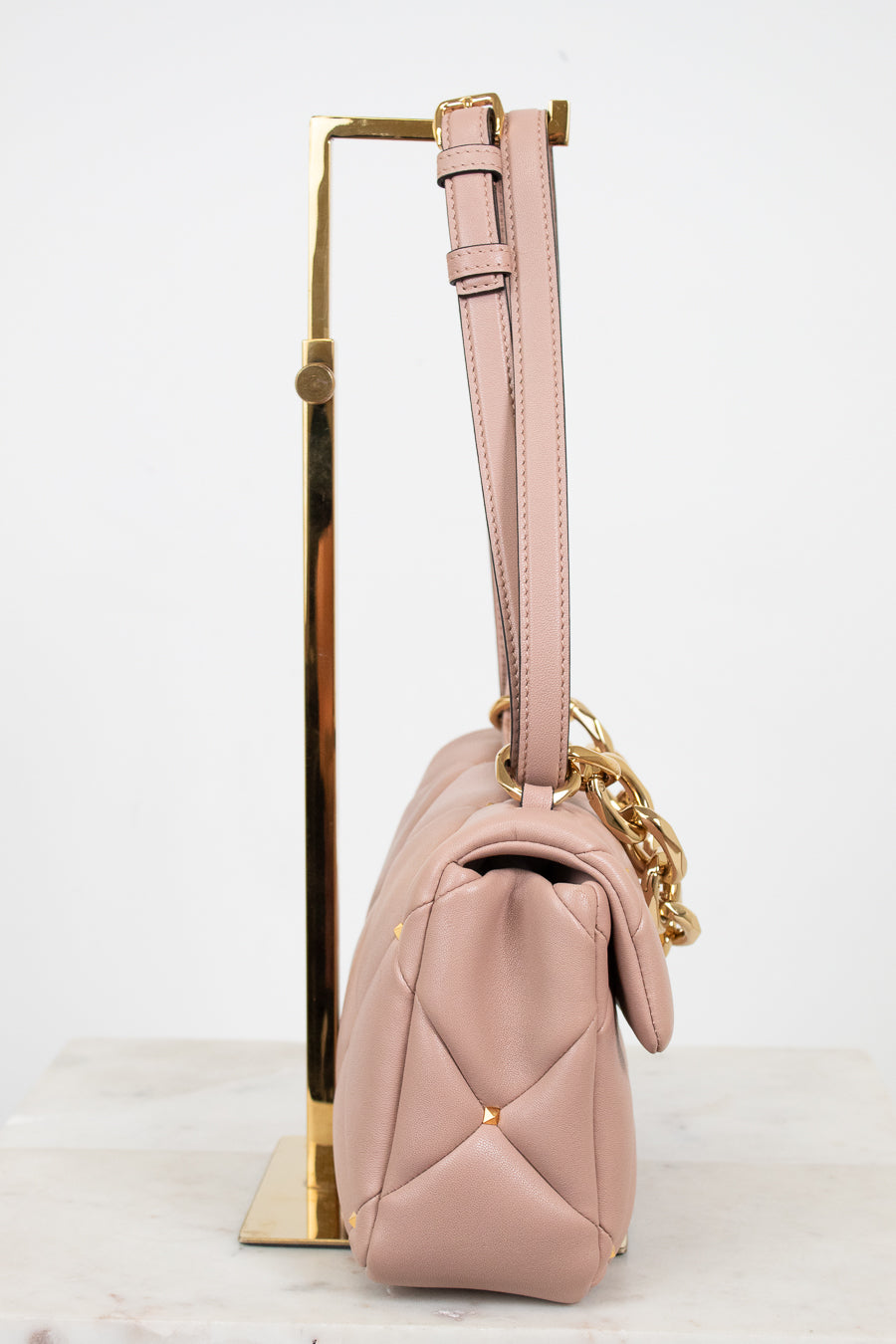 Pink handbag with gold chain on a white background