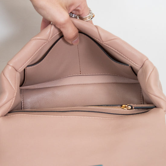 Close-up of a pink handbag with a gold zipper and visible brand logo on a white background.