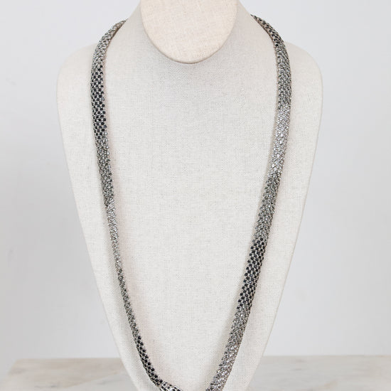 Long chain necklace on a mannequin bust against a white background