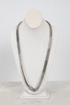 Long chain necklace on a mannequin bust against a white background