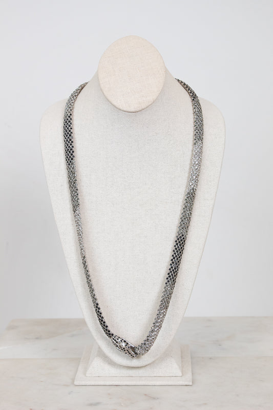 Long chain necklace on a mannequin bust against a white background