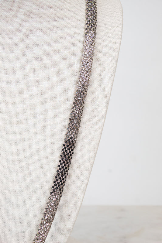 Close-up of a detailed necklace with rhinestone details on a textured fabric background