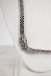 Close-up of a sparkling necklace on a white textured bust