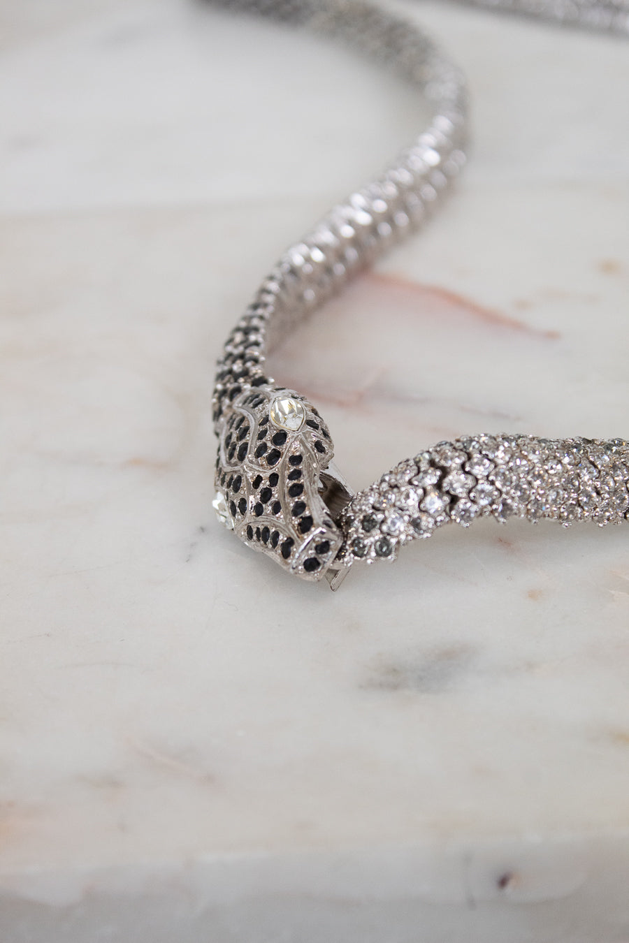 Silver necklace with intricate design on a marble surface