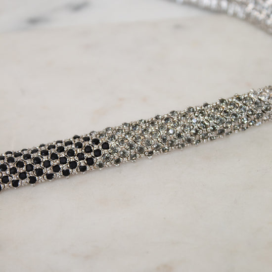 Silver necklace with black and gray rhinestones on a marble surface