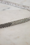 Silver necklace with black and gray rhinestones on a marble surface