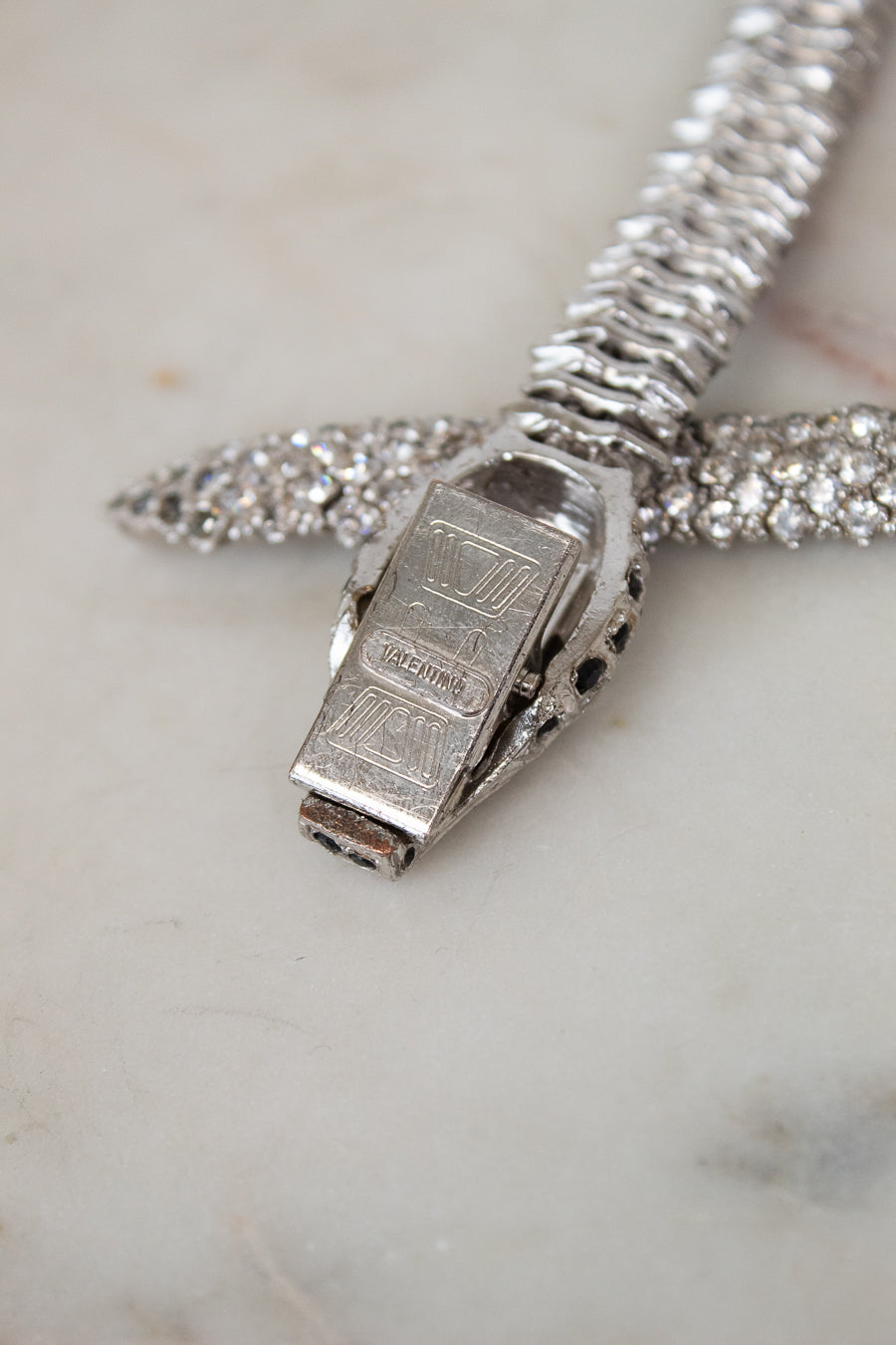 Close-up of a silver bracelet with a clasp on a marble surface