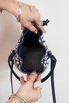 Person holding a navy blue and white patterned handbag on a light background