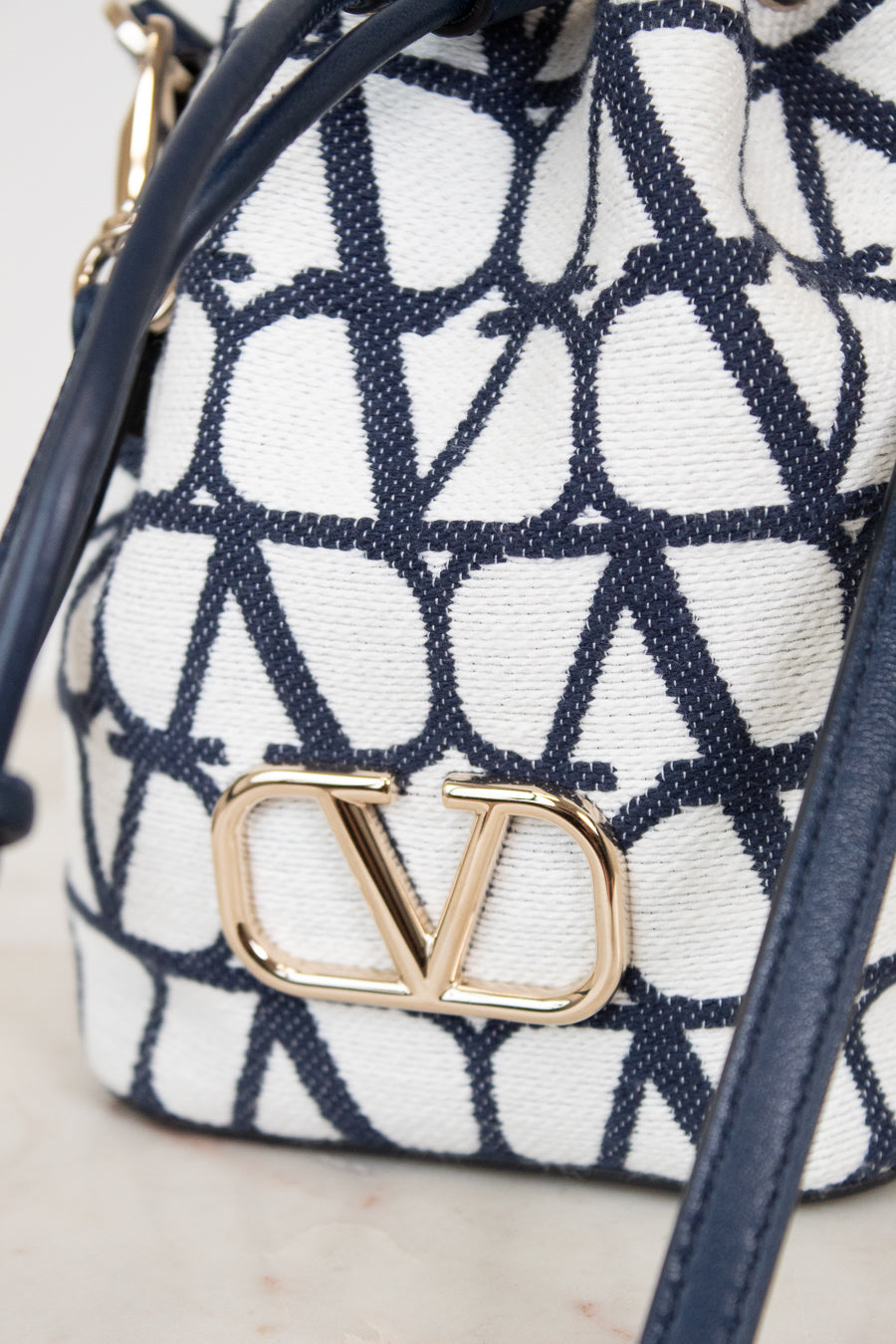 Navy and white patterned bag with gold logo on a light background