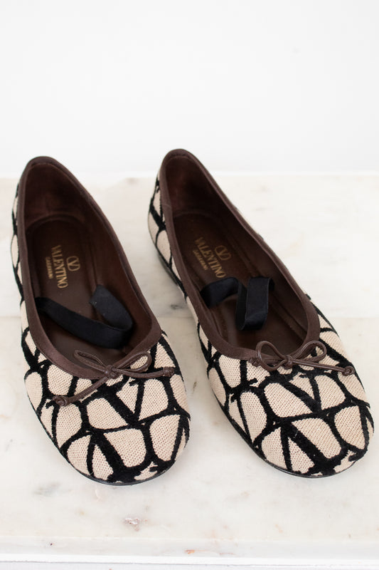 Pair of patterned flats with a bow on a white surface