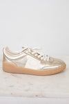 Side view of cream and gold low top sneakers