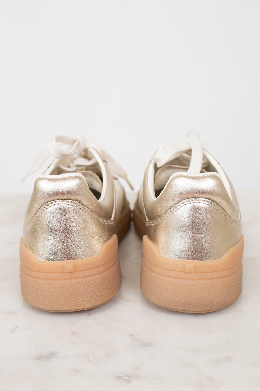 Heel view of gold sneakers with gum soles