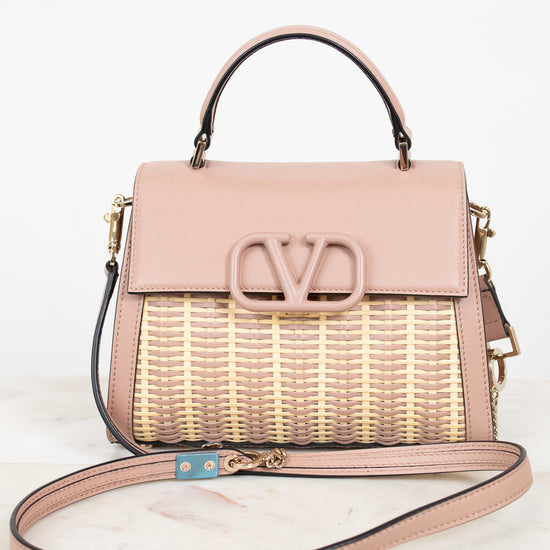 Pink handbag with woven design and visible brand logo on a white background