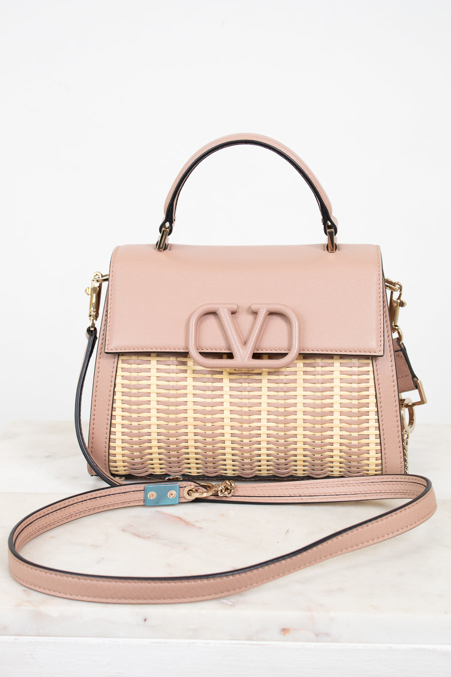 Pink handbag with woven design and visible brand logo on a white background