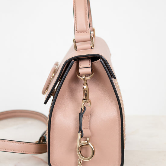 Pink handbag with a gold keychain on a light background