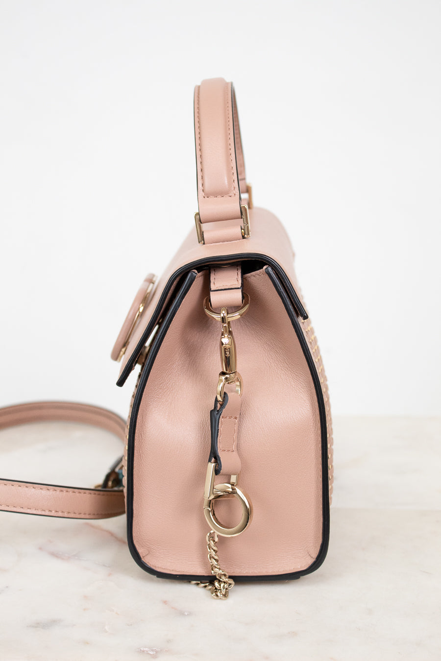 Pink handbag with a gold keychain on a light background