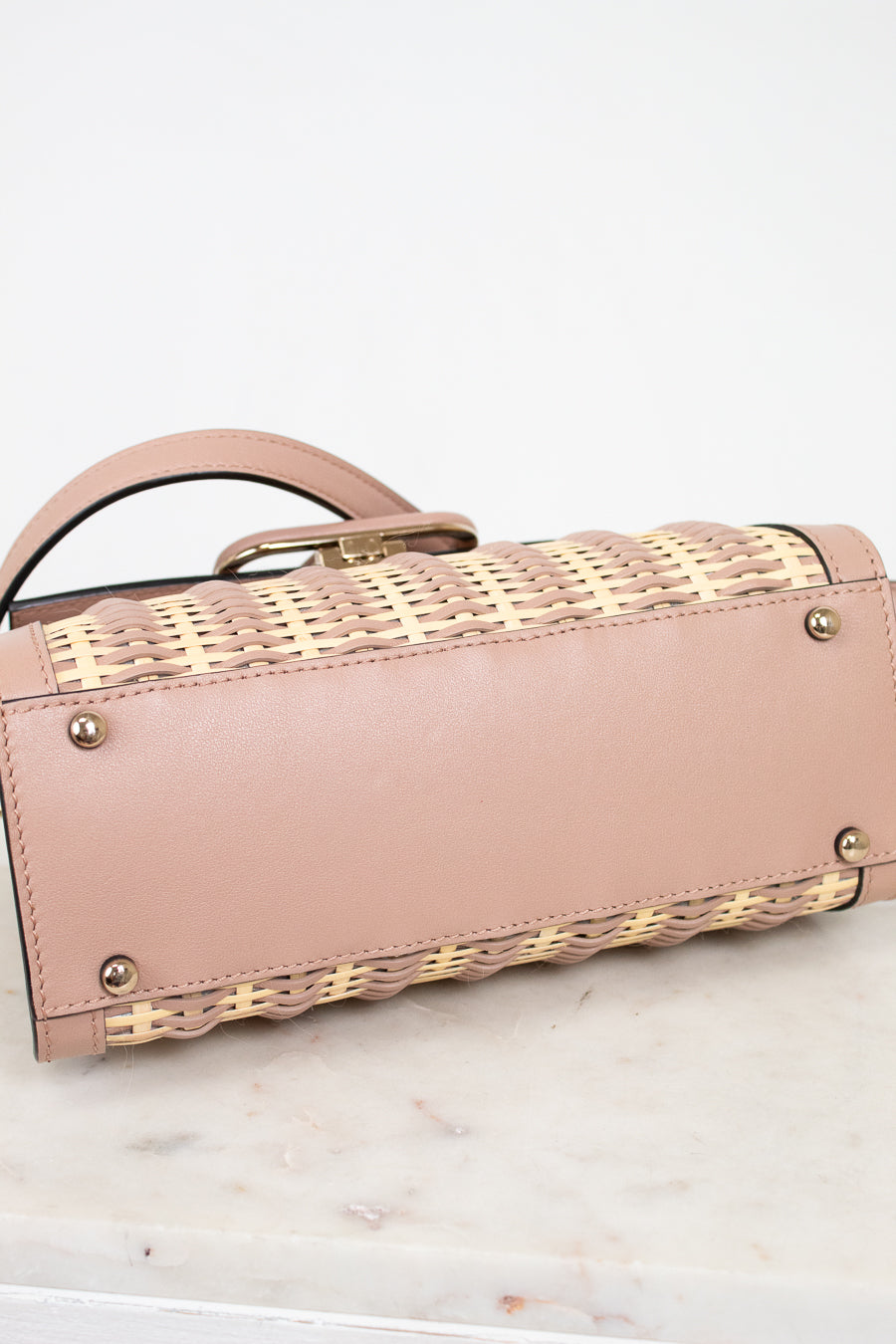 Pink handbag with woven pattern on a marble surface