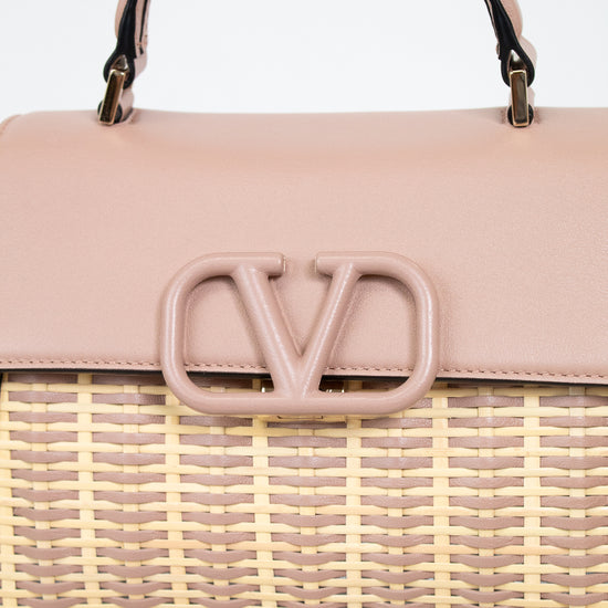 Pink handbag with woven design and visible logo on a light background