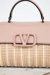 Pink handbag with woven design and visible logo on a light background
