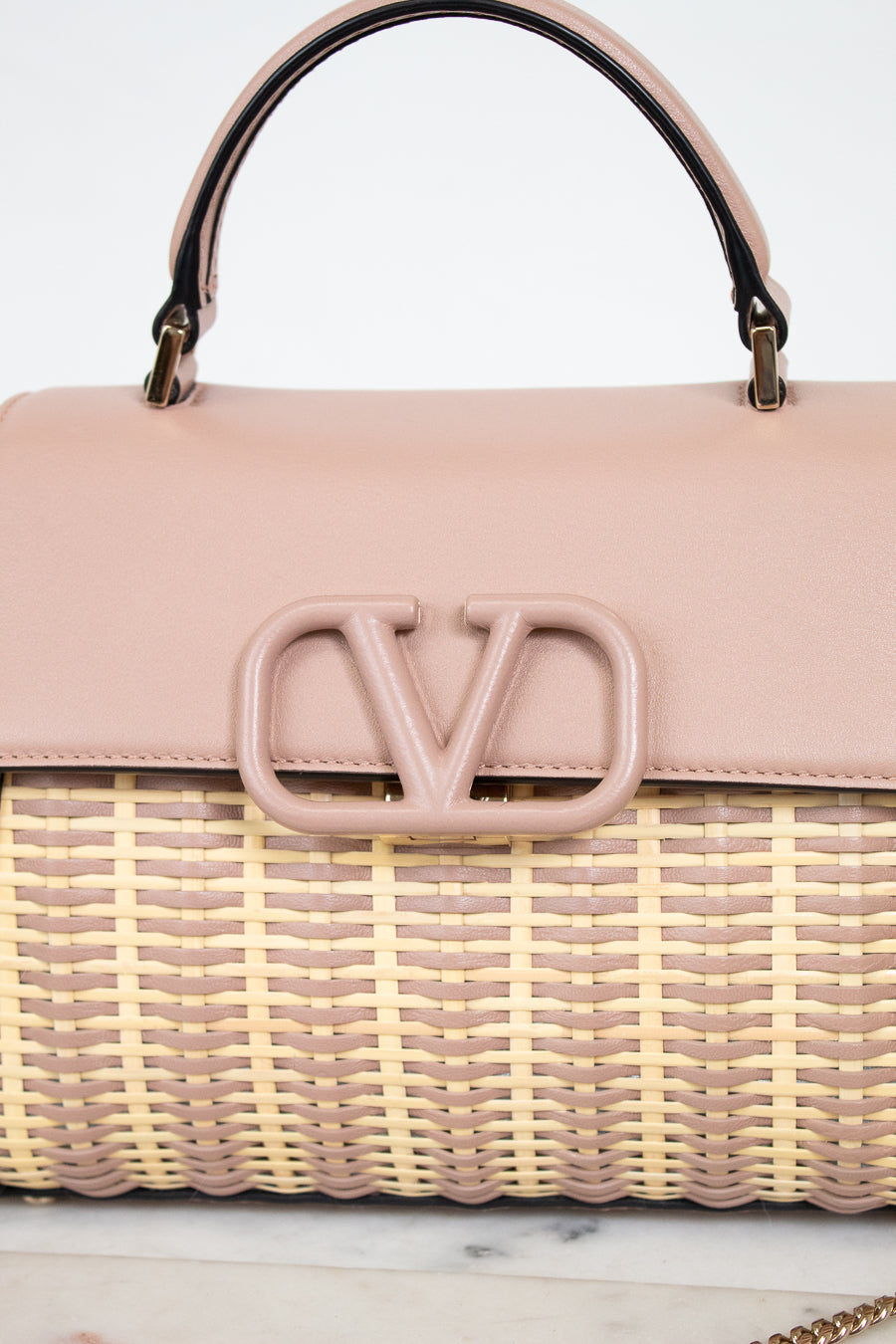 Pink handbag with woven design and visible logo on a light background