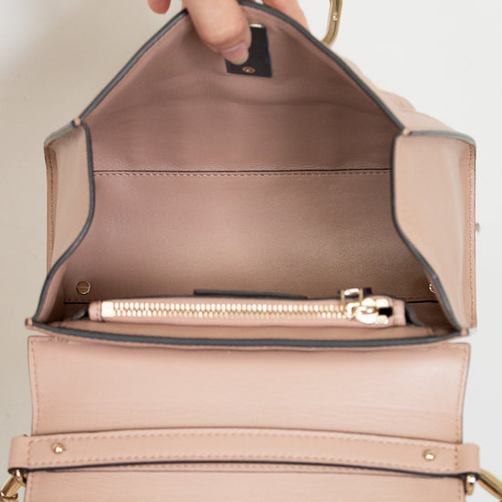 Beige handbag with gold trim, open to reveal interior.