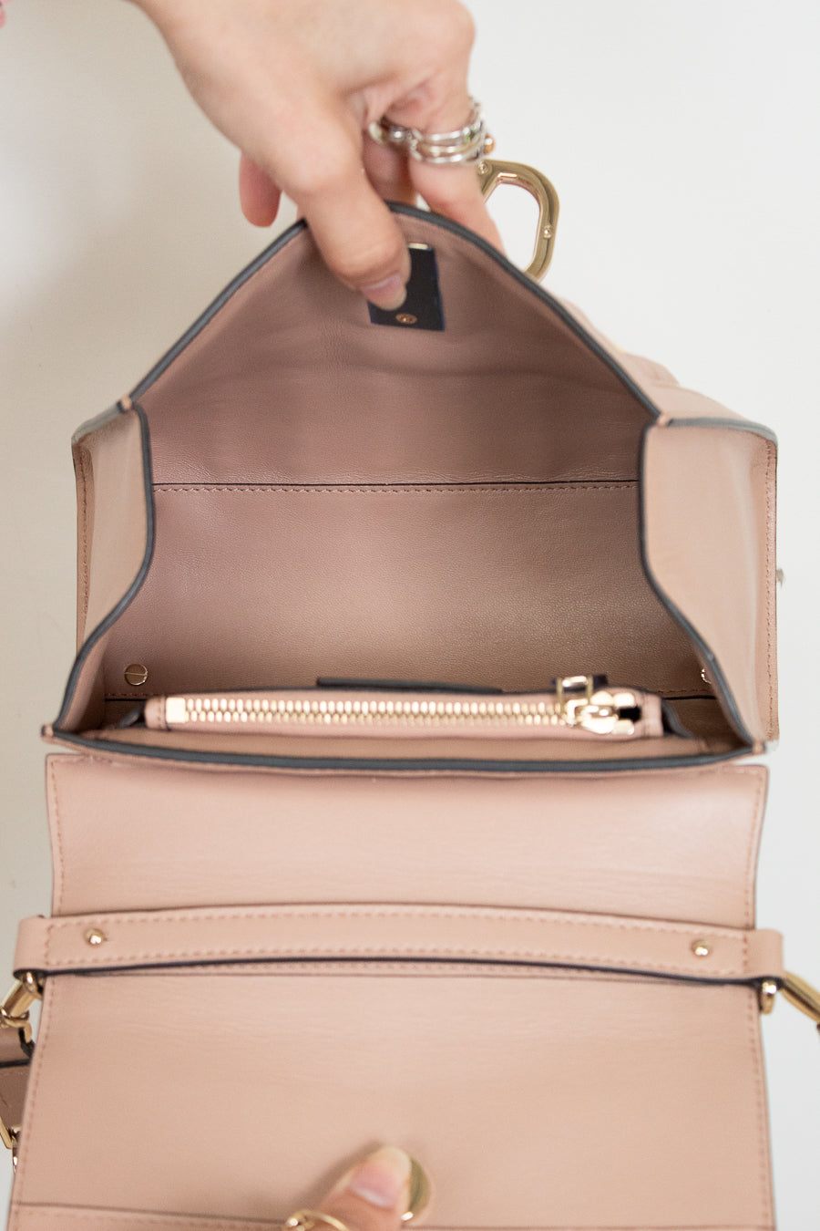 Beige handbag with gold trim, open to reveal interior.