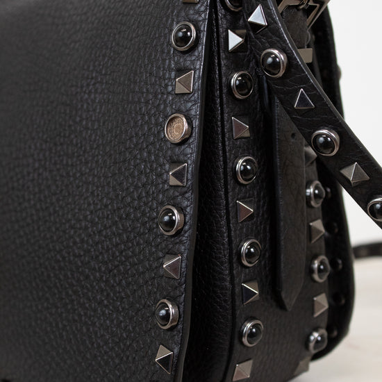Black leather handbag with studded details on a white background