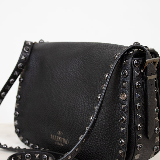 Black leather handbag with studded details on a white background