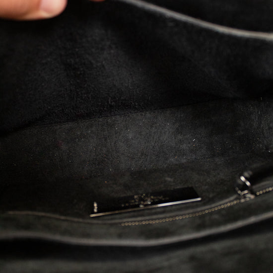 Close-up of a black handbag with a hand opening it
