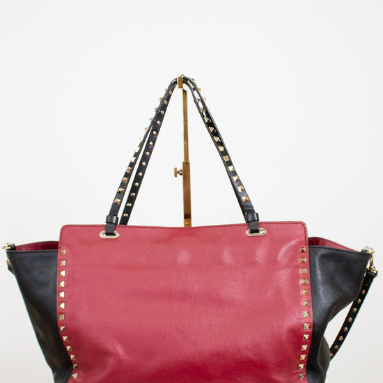 Red and black handbag with studded details on a white background