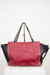 Red and black handbag with studded details on a white background