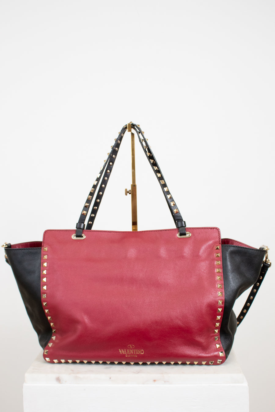 Red and black handbag with studded details on a white background