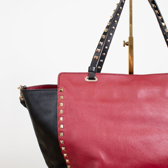 Red handbag with black accents and studded details on a white background