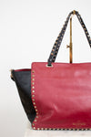 Red handbag with black accents and studded details on a white background