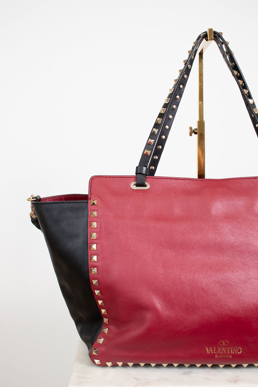 Red handbag with black accents and studded details on a white background