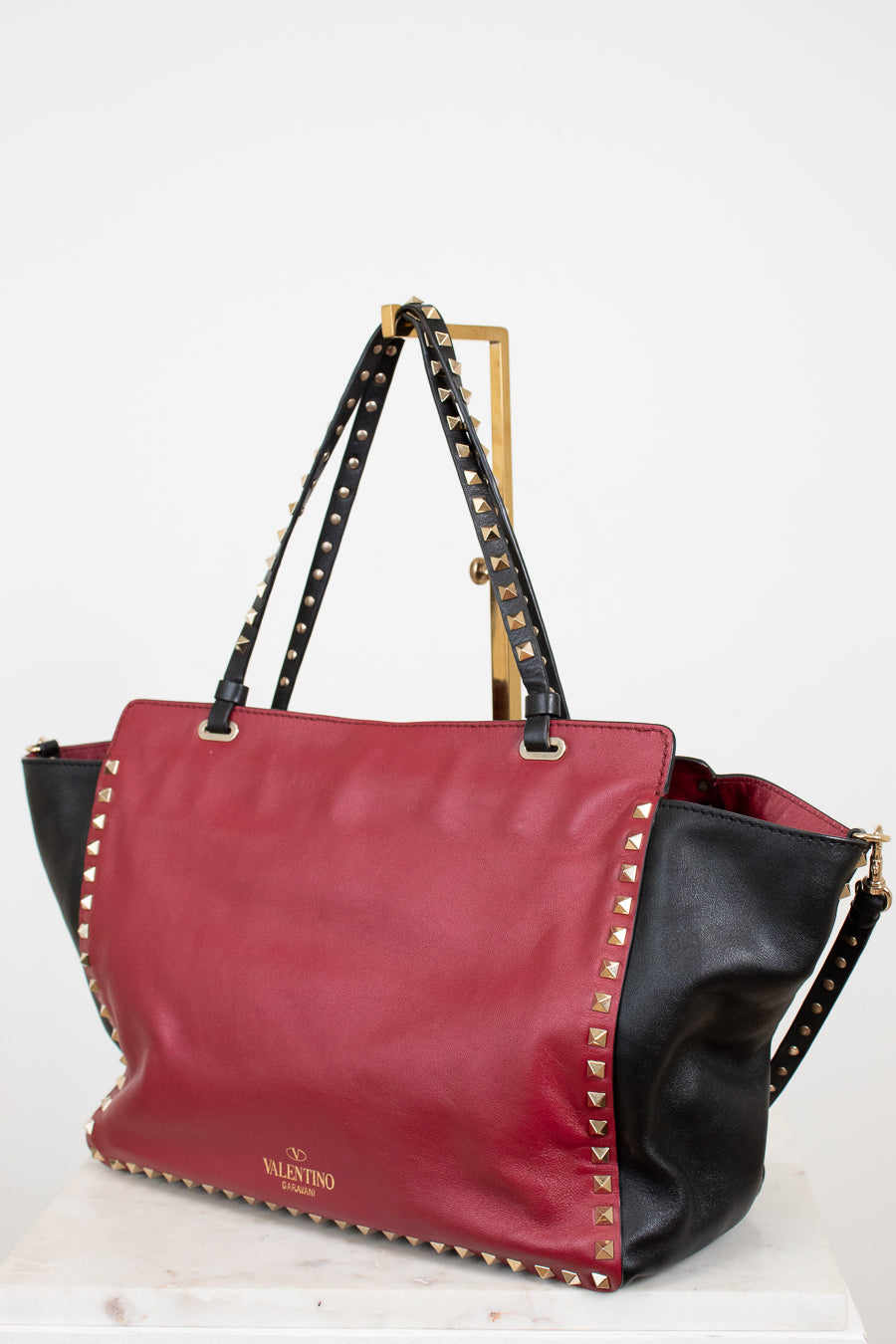 Red and black handbag with studded details on a white background