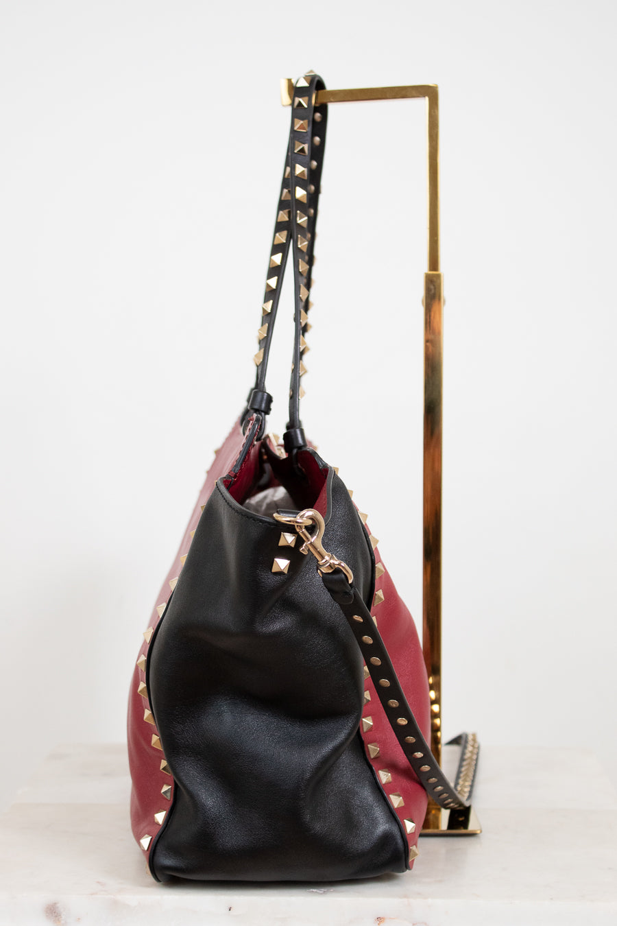 Black and red handbag with studded details on a white background