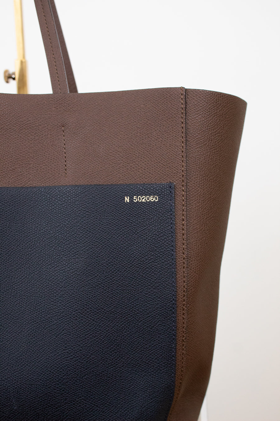 Brown tote bag with a visible brand logo on a white background
