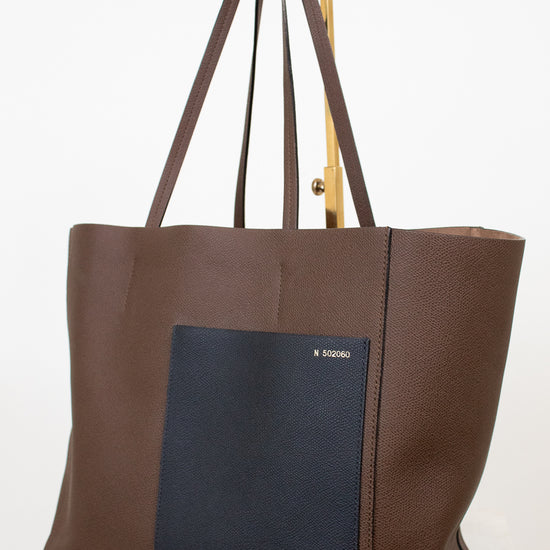 Brown tote bag with a black pocket on a white background