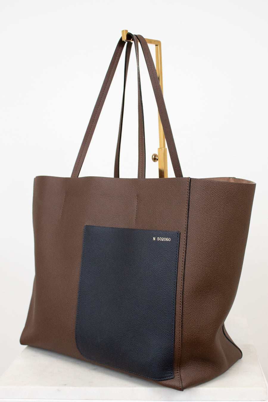 Brown tote bag with a black pocket on a white background