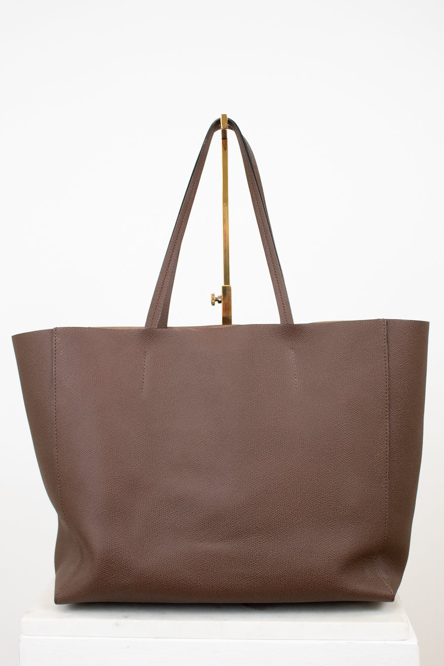 Brown tote bag with a gold clasp on a white background
