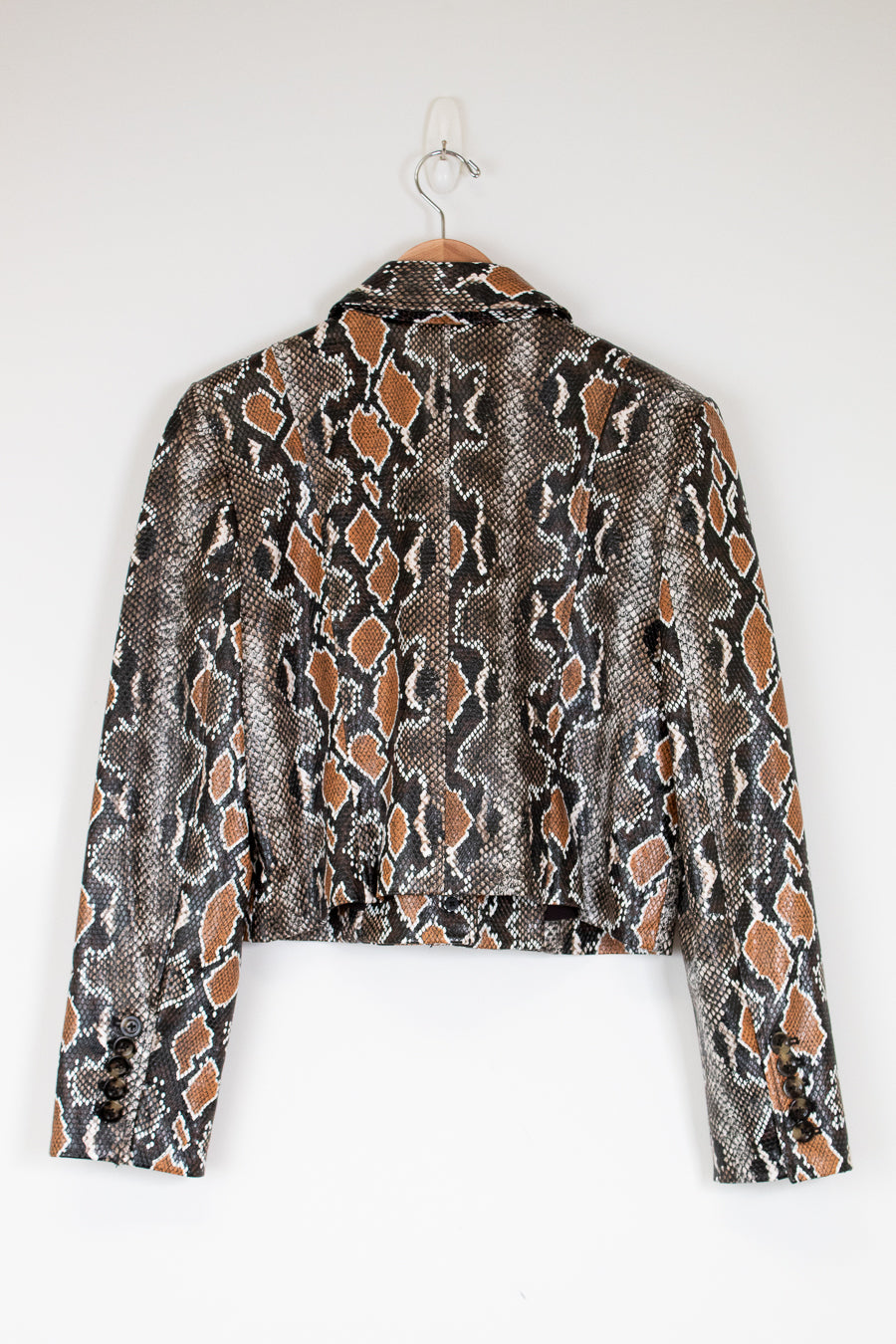 Snakeskin patterned jacket on a hanger against a white background