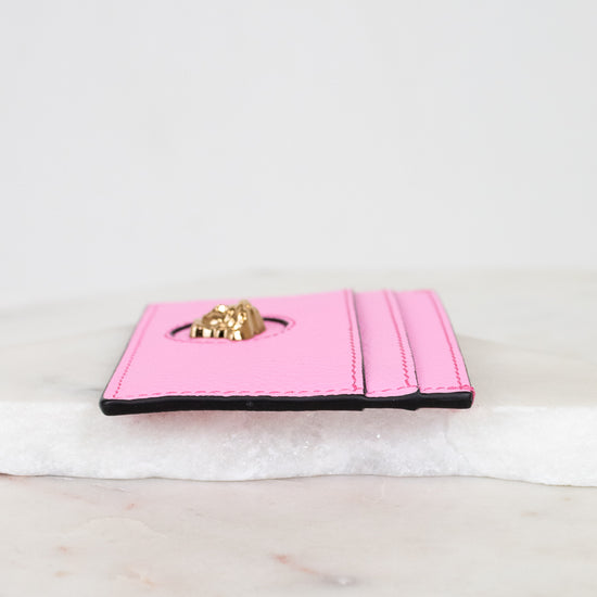 Pink wallet with gold logo on a marble surface