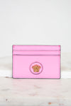 Pink cardholder with a gold logo on a marble surface