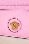 Close-up of a pink leather textured surface with a gold emblem in the center.