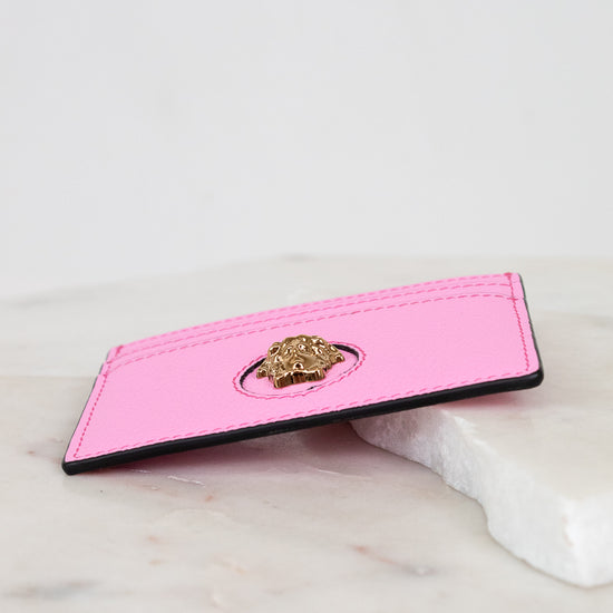 Pink cardholder with gold lion emblem on a marble surface