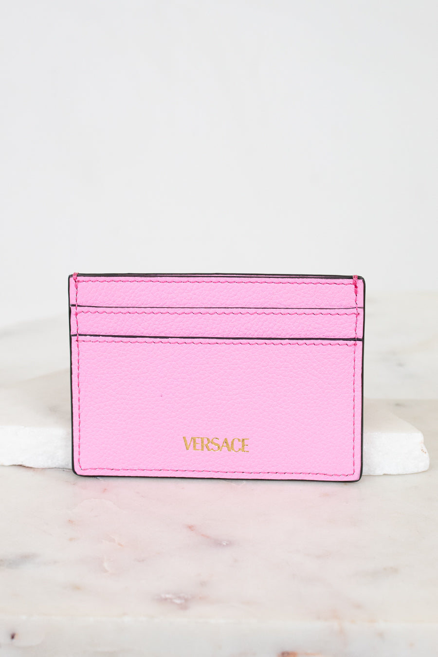 Pink Versace cardholder on a light marble background