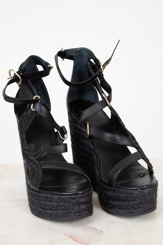 Black platform wedge sandals with espadrille sole on a light background