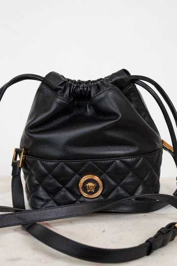 Black quilted drawstring bag with brand logo on a light background