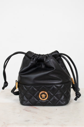 Black quilted drawstring bag with brand logo on a light gray background